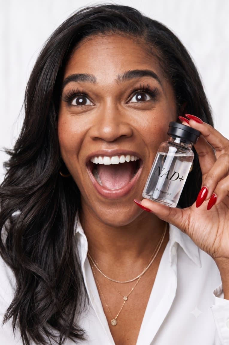 Woman holding a Body Good NAD+ vial against a cream background